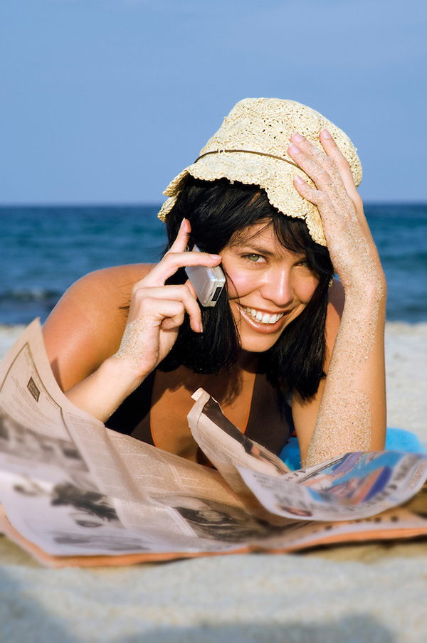 Young fun fit smiling happy beautiful woman on holiday suntanning in a straw hat at the beach talking on her mobile cellphone Telefon je tvoj saveznik: 11 saveta za flert putem sms poruka