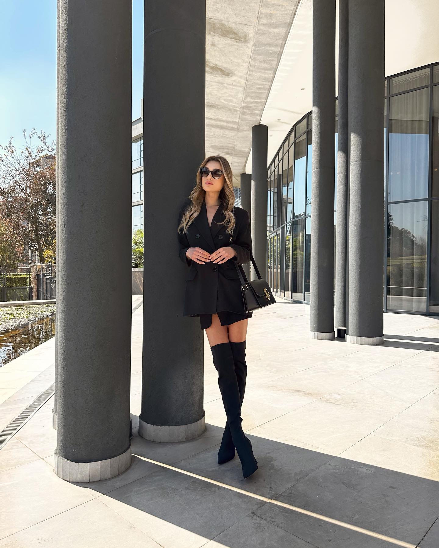 A beautiful girl wearing a fashionable outfit standing at a luxury hotel in South Africa Johannesburg called the houghton. She is wearing a trendy black coach handbag to finish off the look 1 Trendovi za party sezonu: Šta čemo nositi na svim prazničnim zabavama?